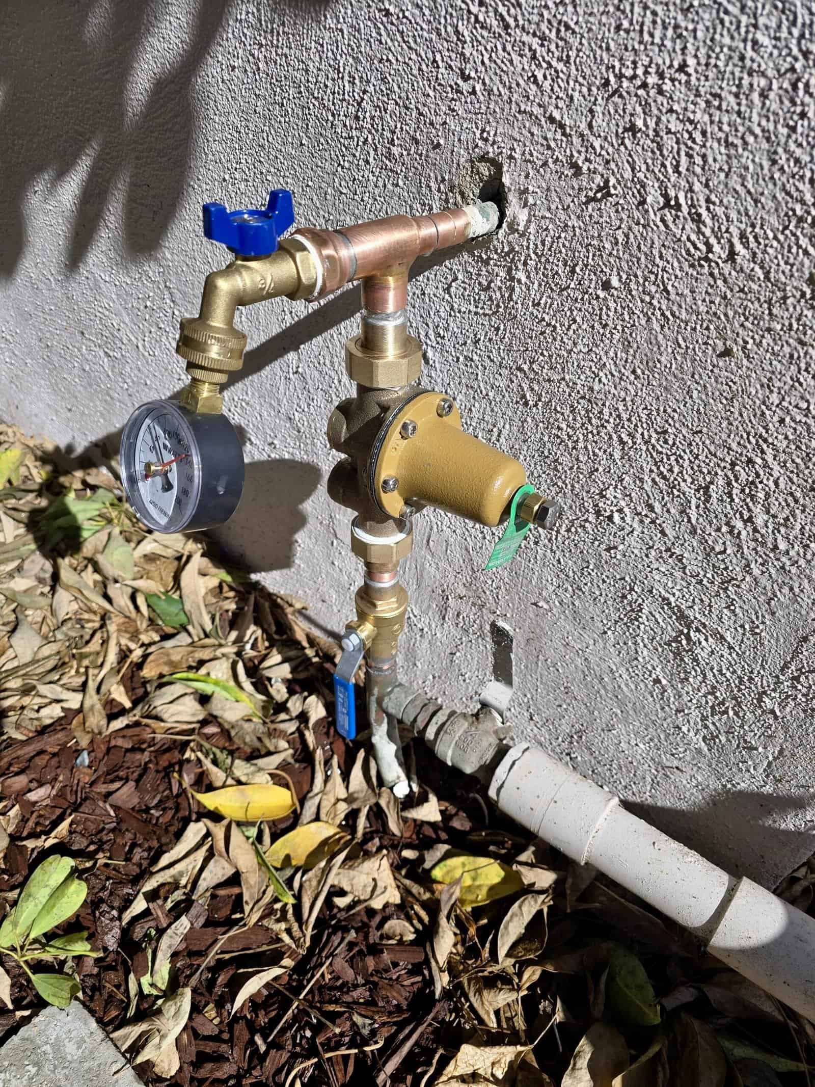 Plumbing valve and pipe system on exterior wall for water control.